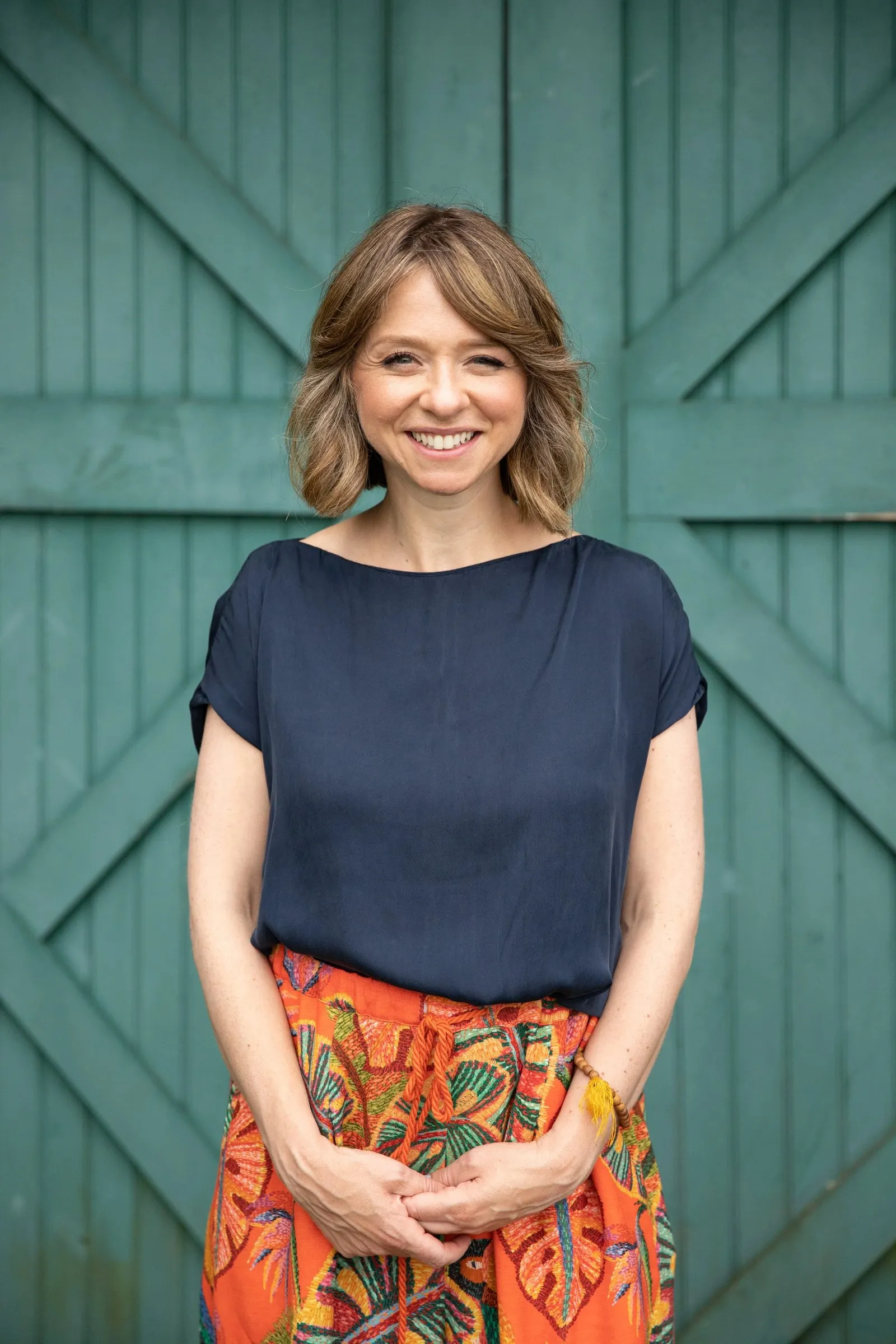 Yael Shy smiling in front of a green wooden door