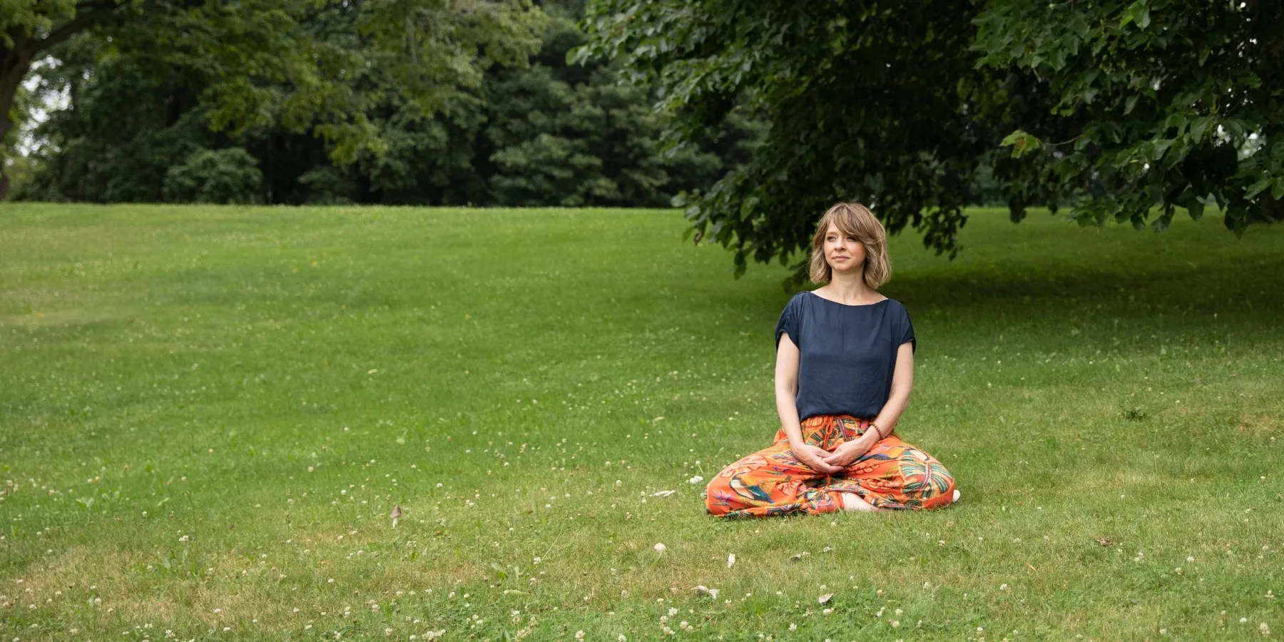 Yael Shy meditating on the grass in a park